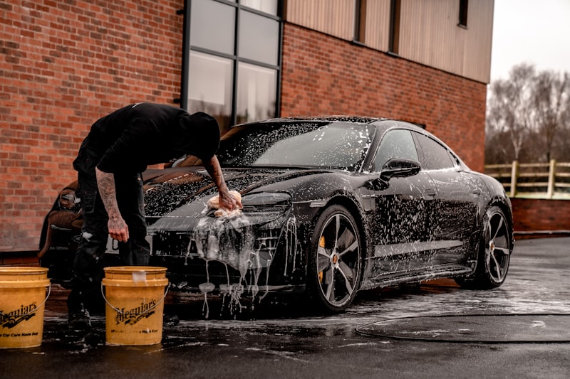 Professional detailer working on a vehicle exterior with foam